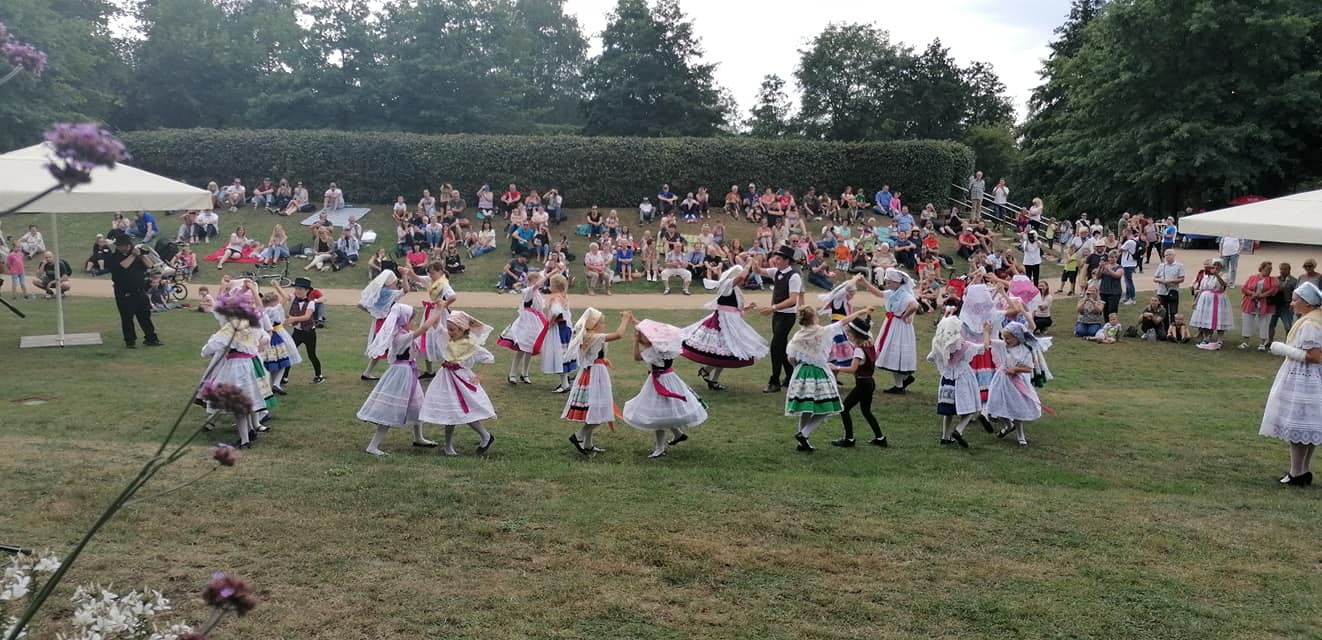 Kinder und Jugendliche tanzen beim sorbisch/wendischen Literatur- und Musikfest 2021 auf einer Wiese in sorbischer Tracht.